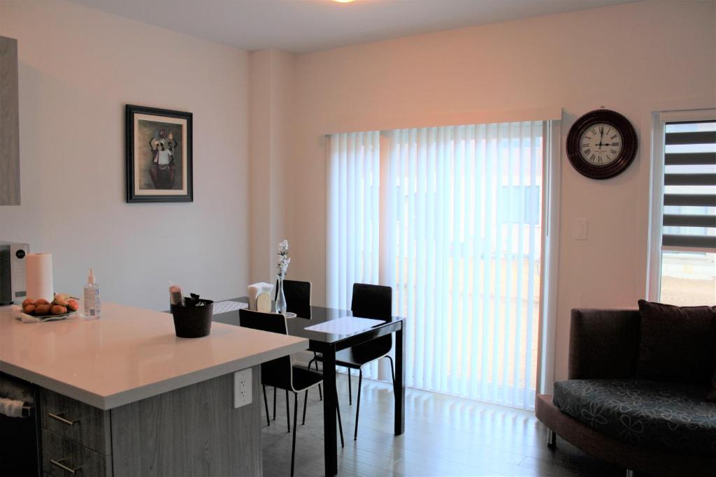 a kitchen and living room with a table and a clock at New Town House Barrie South in Barrie