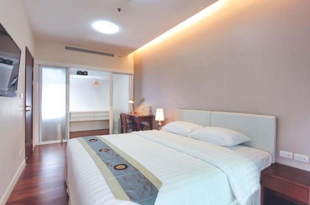 Un dormitorio con una gran cama blanca y una mesa en Citiresort Living sukhumvit 39 en Makkasan