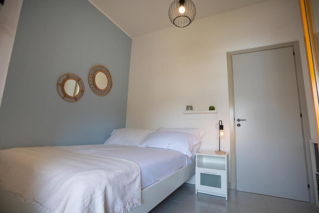 een witte slaapkamer met een bed en een spiegel bij Pausa Mare Seaside in Torre a Mare