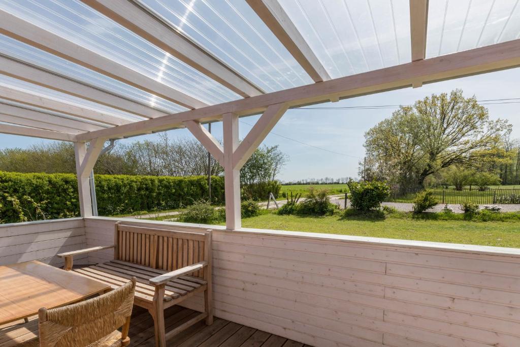 uma pérgola com uma mesa e cadeiras num deque de madeira em Holtdeel em Gelting