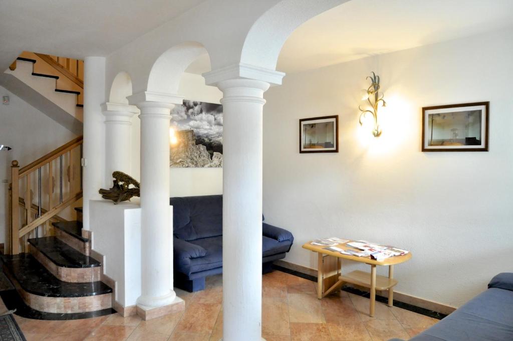 a living room with white columns and a blue couch at Ciasa Mira - BelaVal Apartments in La Villa