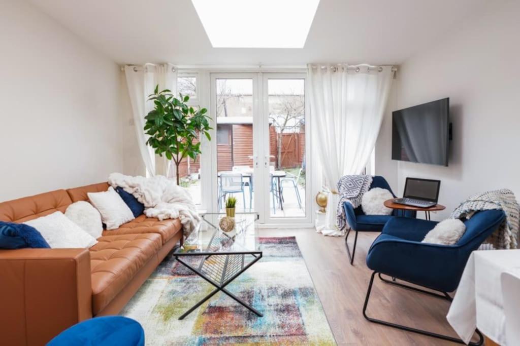 a living room with a brown couch and blue chairs at Newly Renovated Modern 4 Bed 3 Bath Apartment London in London
