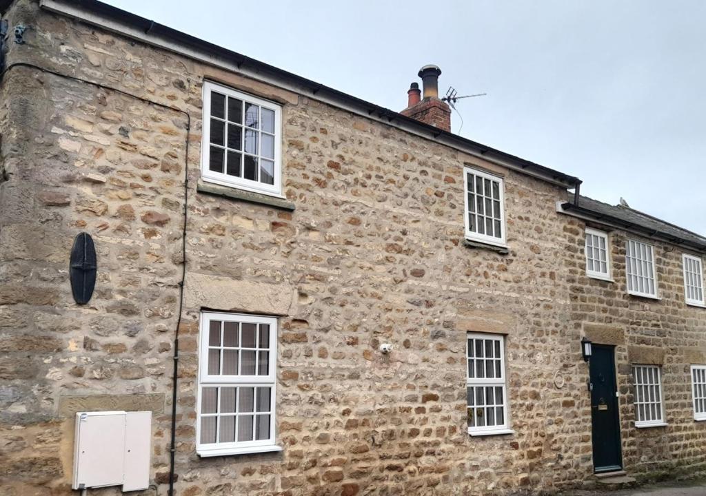 an old brick building with white windows at Barn Owl Cottage in Masham
