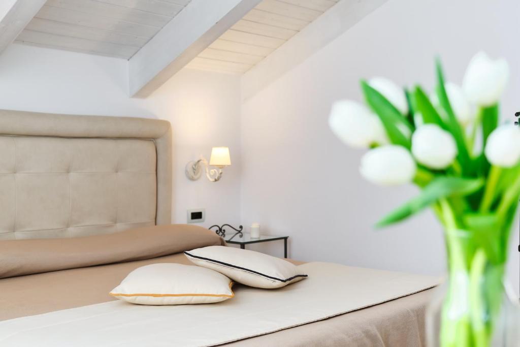 a bed with white pillows and a vase of flowers at Villa Fabiana in Amalfi