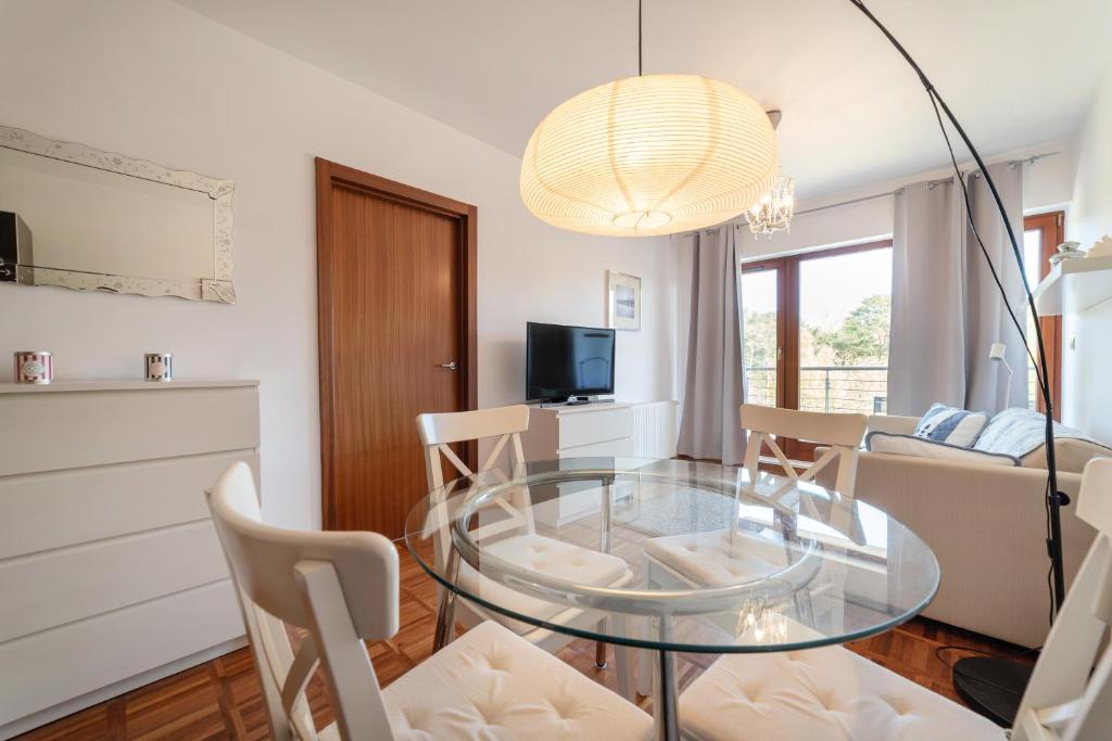 a living room with a glass table and chairs at Nowoczesny Apartament w Helskiej Villi w Helu in Hel