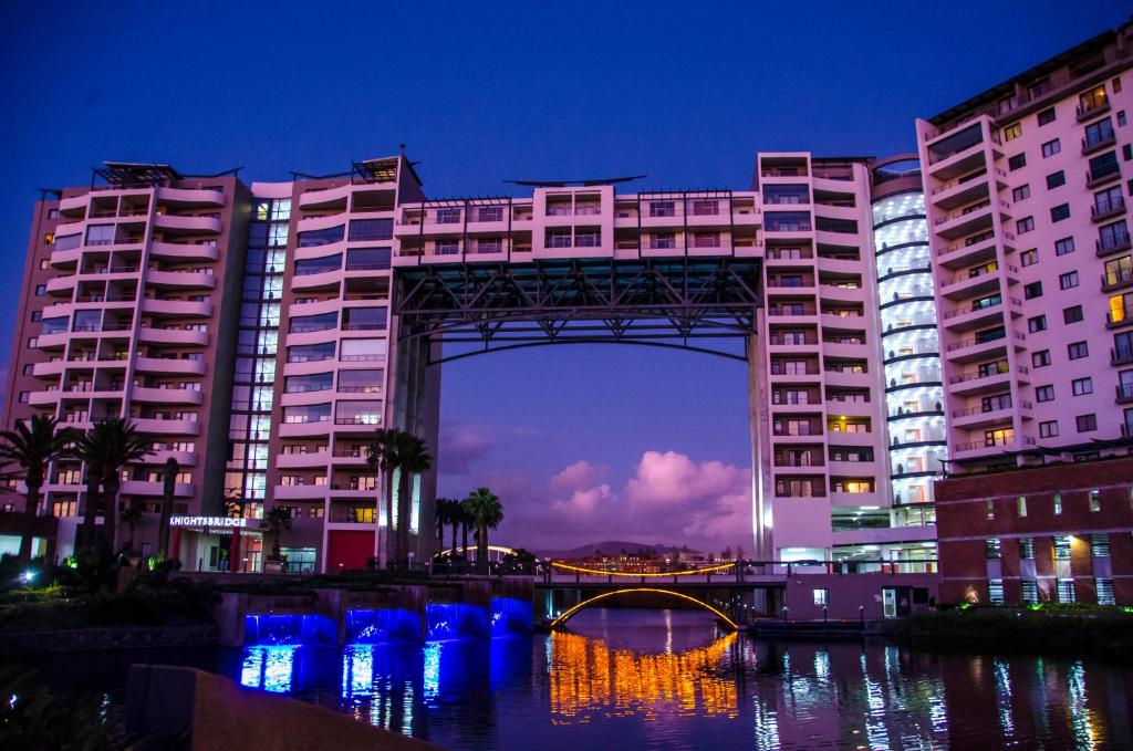 a bridge over a river in front of tall buildings at Knightsbridge Superior Apartments in Cape Town
