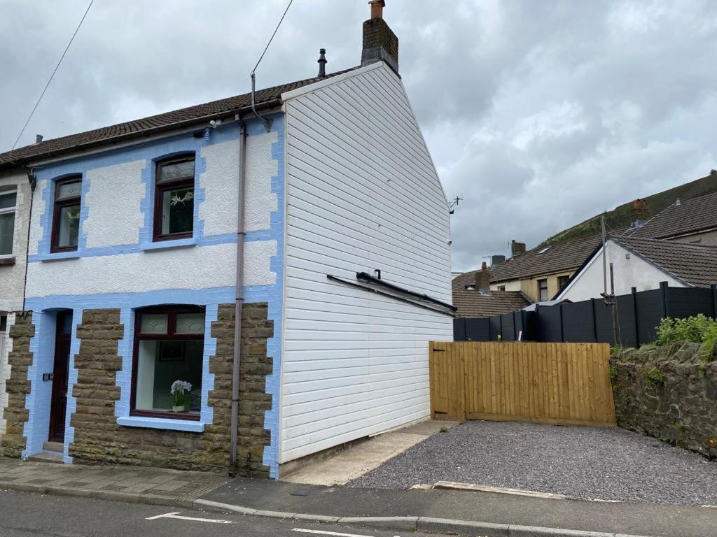 a white and blue house with a wooden fence at Rhondda Tunnel Cottage by StayStaycations in Treorky