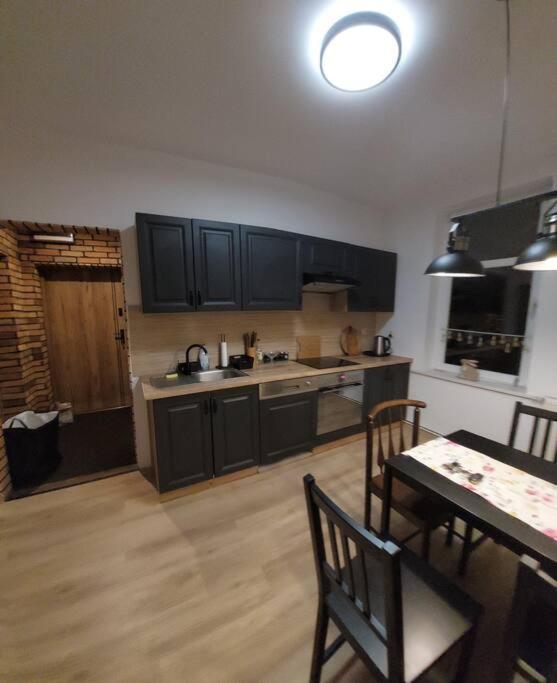 a kitchen with black cabinets and a table and a dining room at Apartament Blisko Granicy in Kunowice