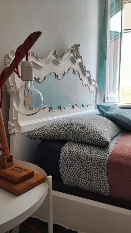 a bed with a white headboard next to a table at La Casetta del Bianconiglio con Garage in Genoa