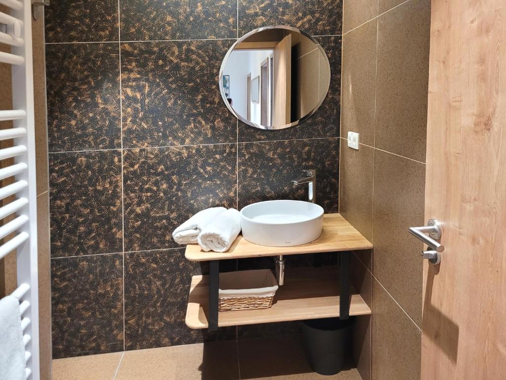 Apartmány U stezek في ليبوفا لازن: حمام مع حوض ومرآة على الحائط