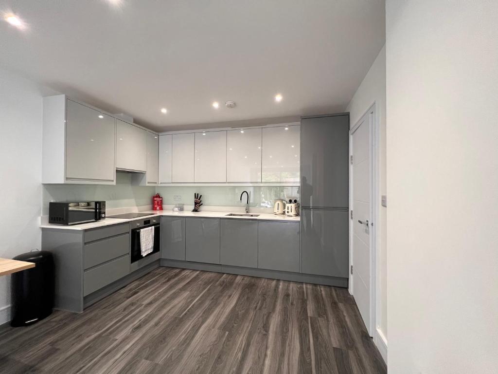 cocina con armarios blancos y suelo de madera en Star London Finchley Lane 3-Bed Residence with Garden, en Hendon