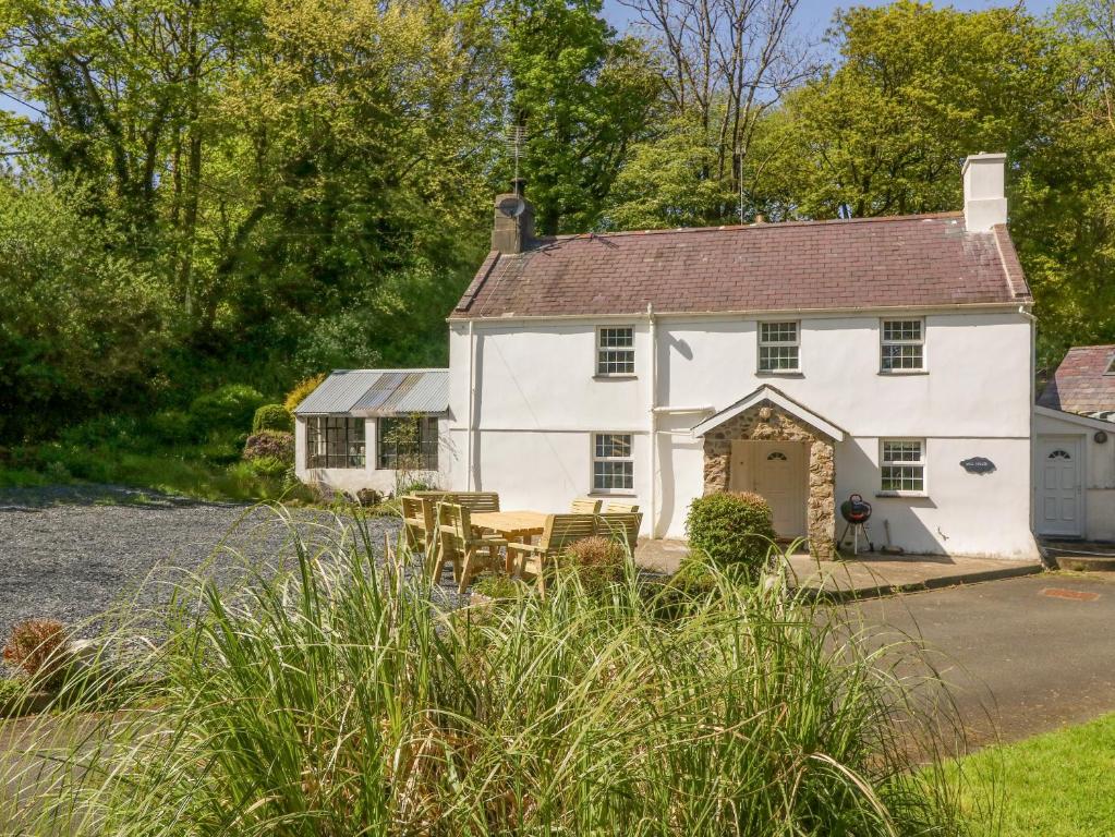 a white house with tables and chairs in front of it at Mill House Main House in Pwllheli