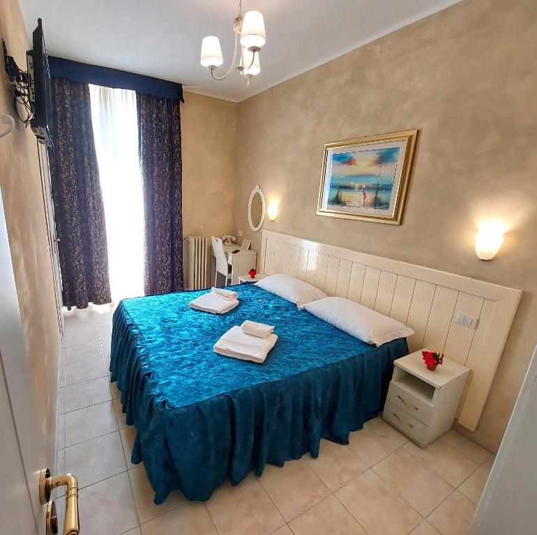 a bedroom with a blue bed with towels on it at Hotel Aurelia Milano Centrale in Milan