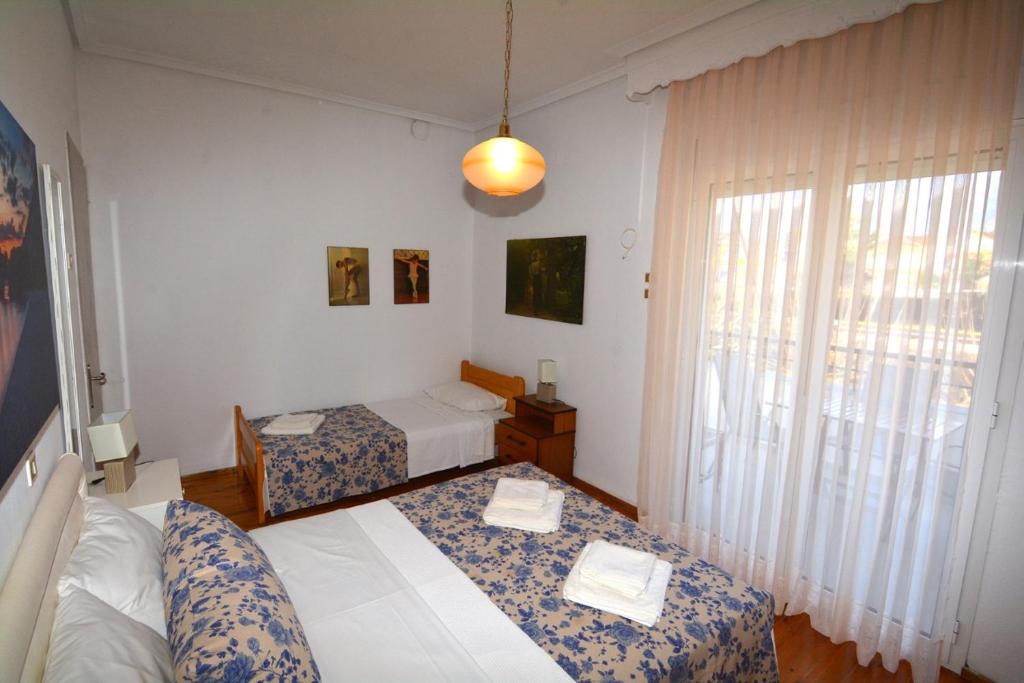 ein Hotelzimmer mit 2 Betten und einem Fenster in der Unterkunft ZeusPlace Georgia Blue in Leptokaryá