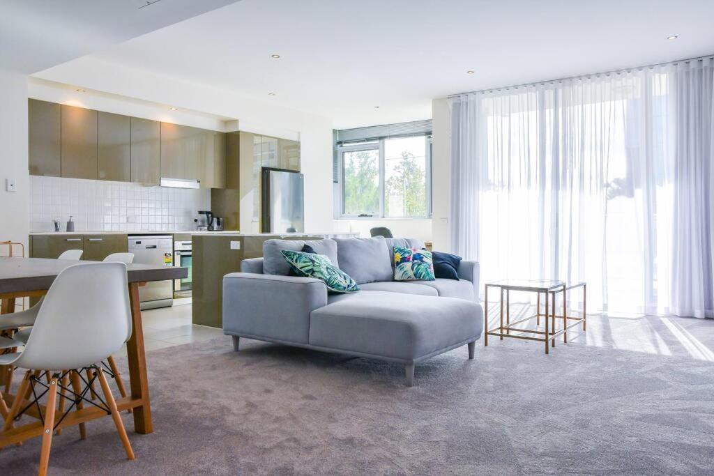 a living room with a couch and a kitchen at Spacious sun-drenched apartment, centrally located in Canberra