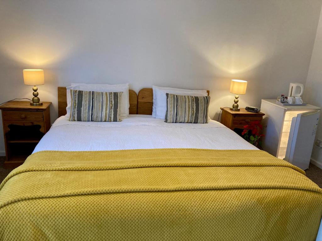 a bedroom with a large bed with yellow sheets and two lamps at Jersey Villa Guest House in Warwick