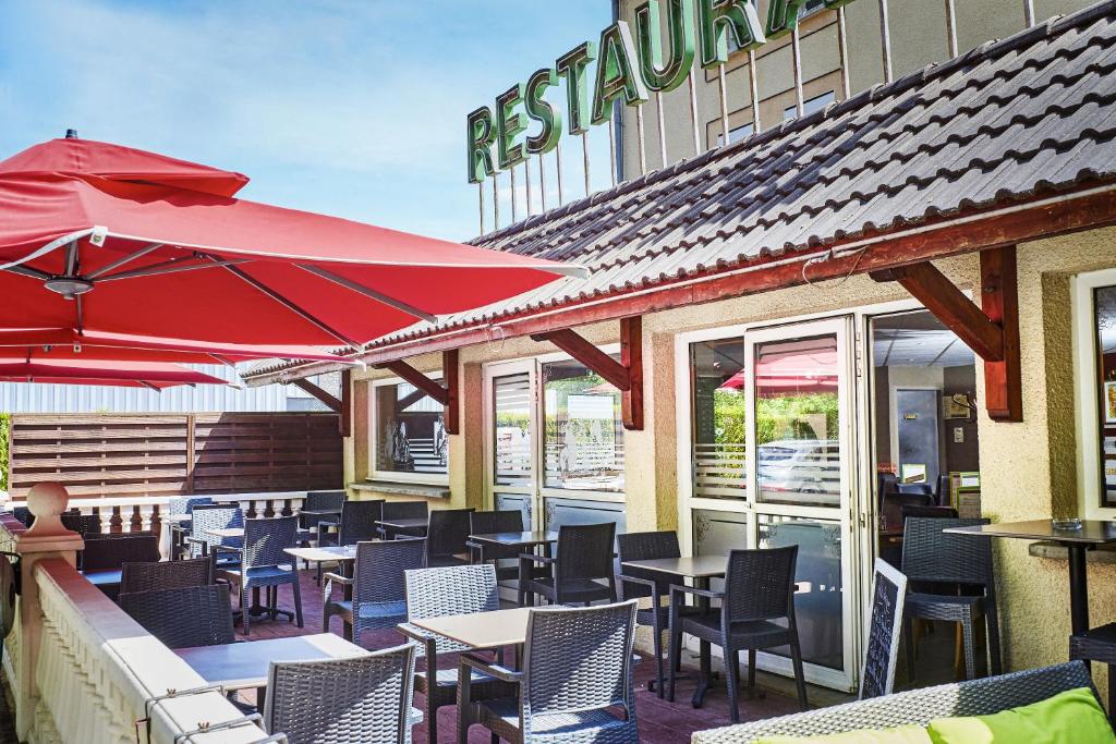 um restaurante com mesas e cadeiras e um guarda-sol vermelho em Logis Bagatelle - 51530 Dizy em Épernay