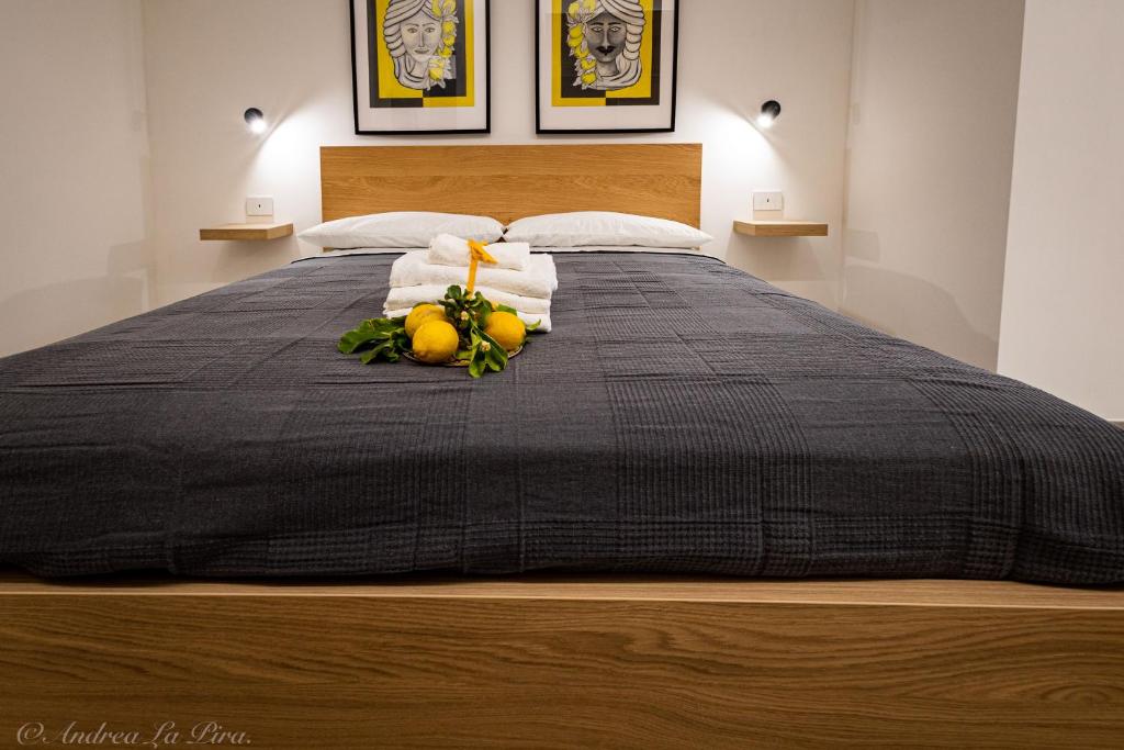 a bed with a black blanket and fruit on it at Sikelia Apartments in Pozzallo