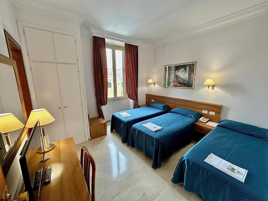 a hotel room with two beds and a table at Hotel Principe Di Piemonte in Rome