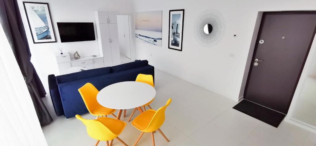 Habitación con mesa blanca y sillas amarillas. en OXYGEN NEPTUN BY BOUTIQUE C5 en Neptun