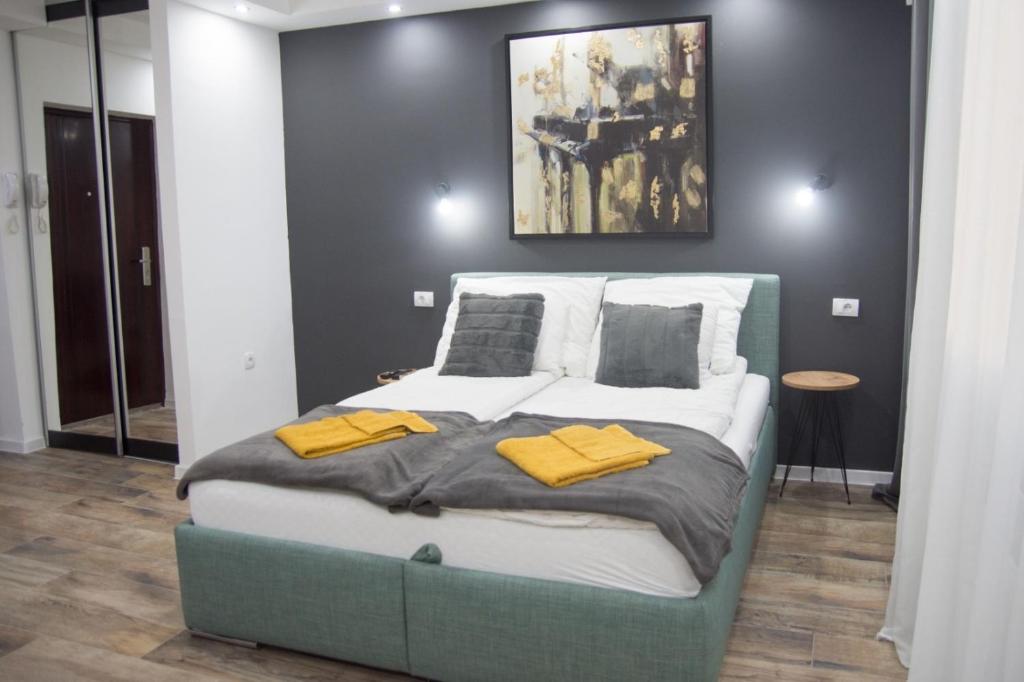 a bedroom with a large bed with yellow towels on it at Apartman Studio GSM in Subotica