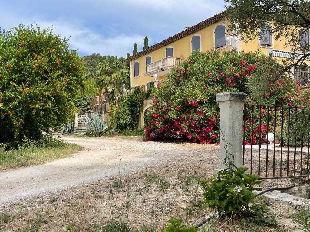 a fence in front of a house with flowers at BASTIDE DU DEFENDS in Pertuis