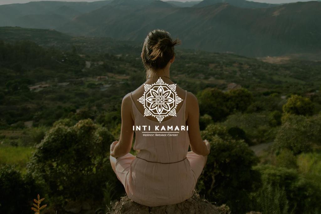 Eine Frau, die auf einem Felsen sitzt und die Berge ansieht. in der Unterkunft Inti Kamari Wellness Lodge & Convention Center in Santa Isabel