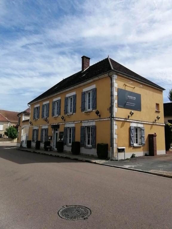 un grand bâtiment jaune sur le côté d'une rue dans l'établissement LOGIS Hôtel & Restaurant Le Soleil D'or, à Montigny-la-Resle