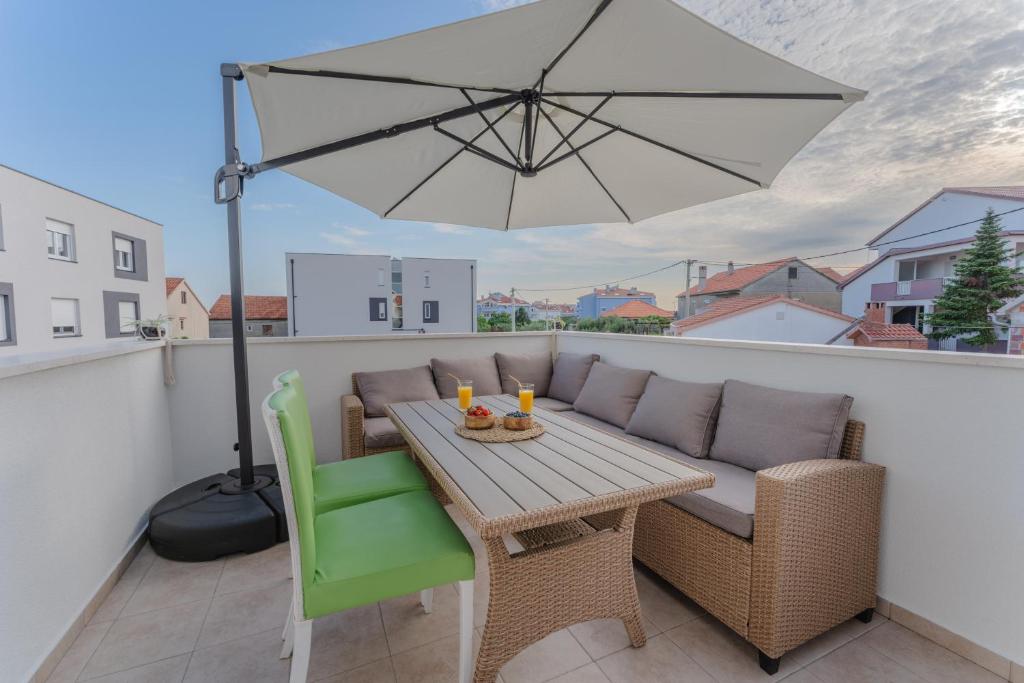 a patio table with an umbrella on a balcony at Apartment Glamorous Getaway in Zadar