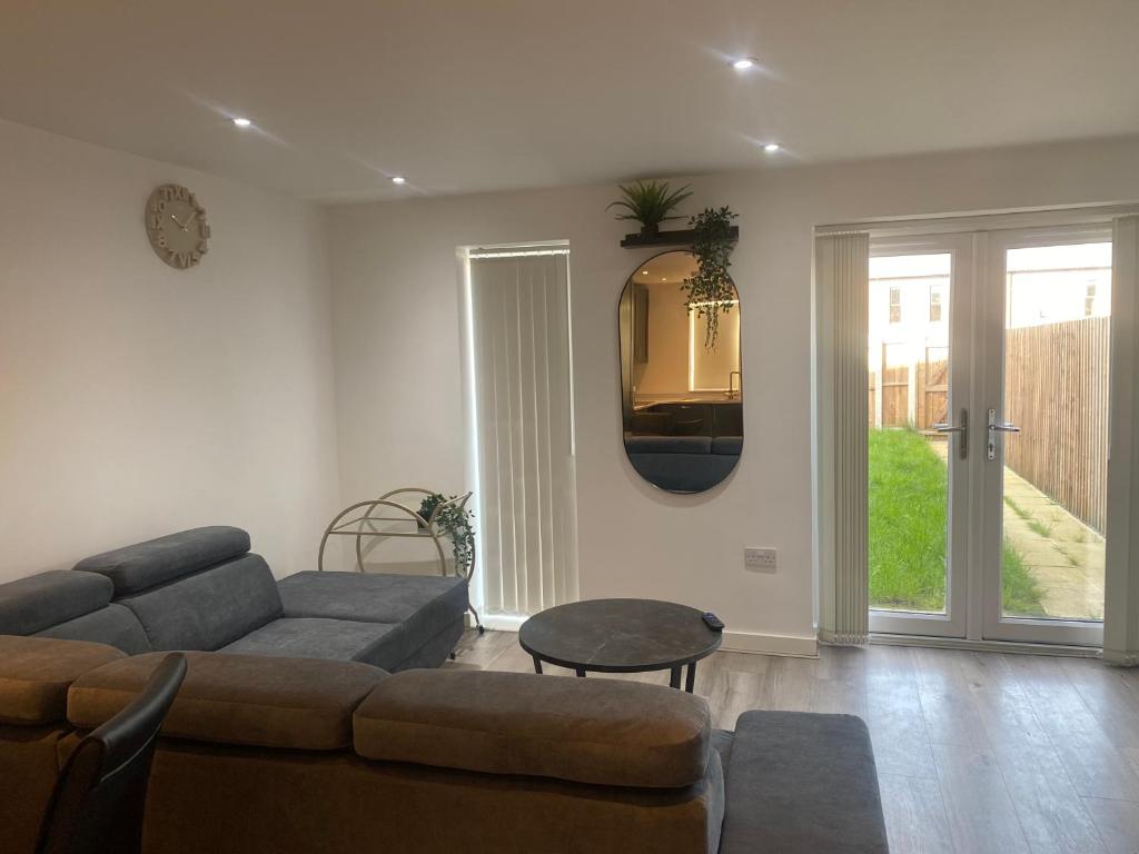 Eaglet luxury home في مانشستر: غرفة معيشة مع أريكة وطاولة ومرآة
