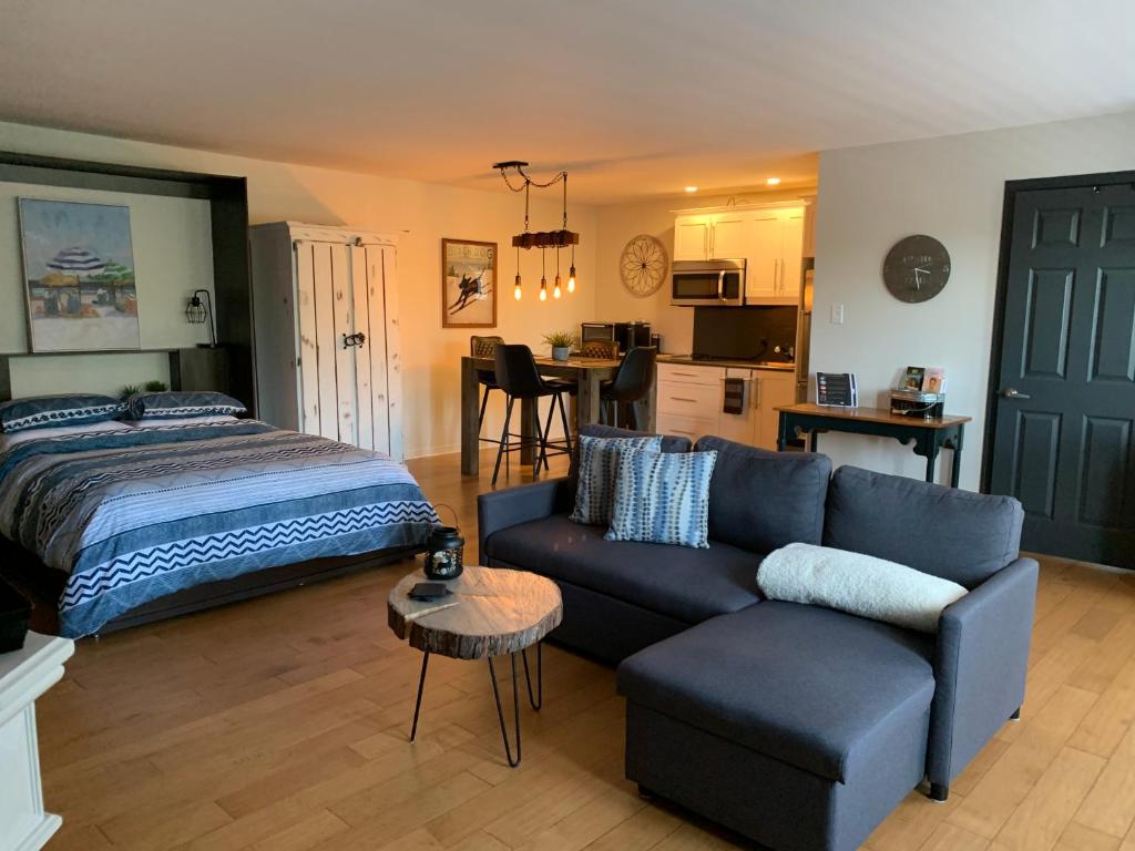 a bedroom with a couch and a bed and a kitchen at L'Authentique in Orford