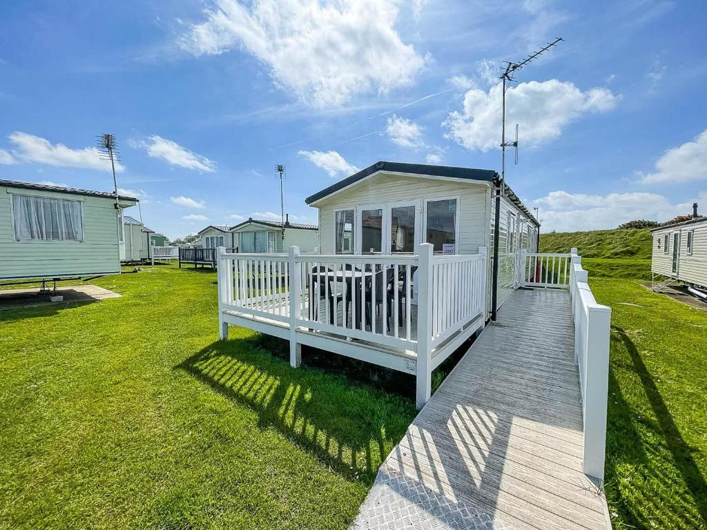 a white house with a porch and a deck at 8 Berth Caravan With Decking To Hire At Naze Marine In Essex Ref 17280c in Walton-on-the-Naze