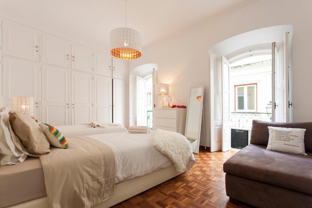 Habitación blanca con cama y sofá en Ginjinha House - 4 Rooms - Bairro Alto - with AC!, en Lisboa