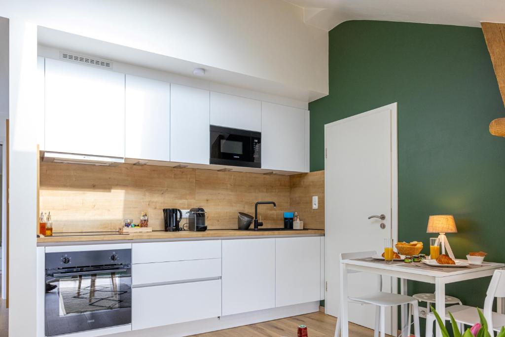 una cocina con armarios blancos y una pared verde en Gîte Le Haut des Vannes en Neufchâteau