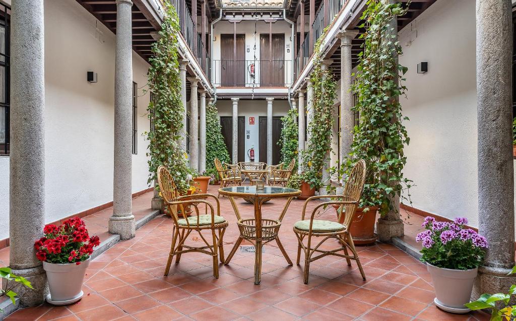 un patio avec des tables, des chaises et des plantes dans l'établissement ADANAR-Las Columnas, à Grenade