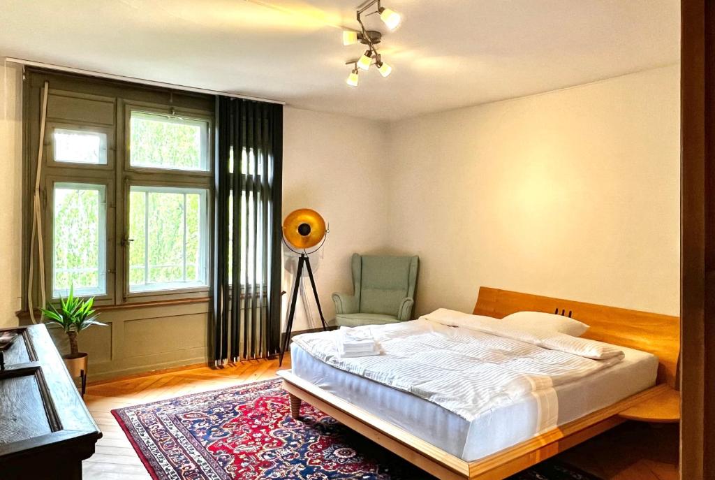 1 dormitorio con 1 cama, 1 silla y 1 ventana en Villa Bergruh, en St. Gallen