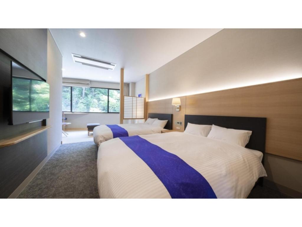 a bedroom with two beds and a flat screen tv at Hotel Sekisuien - Vacation STAY 44687v in Gujo