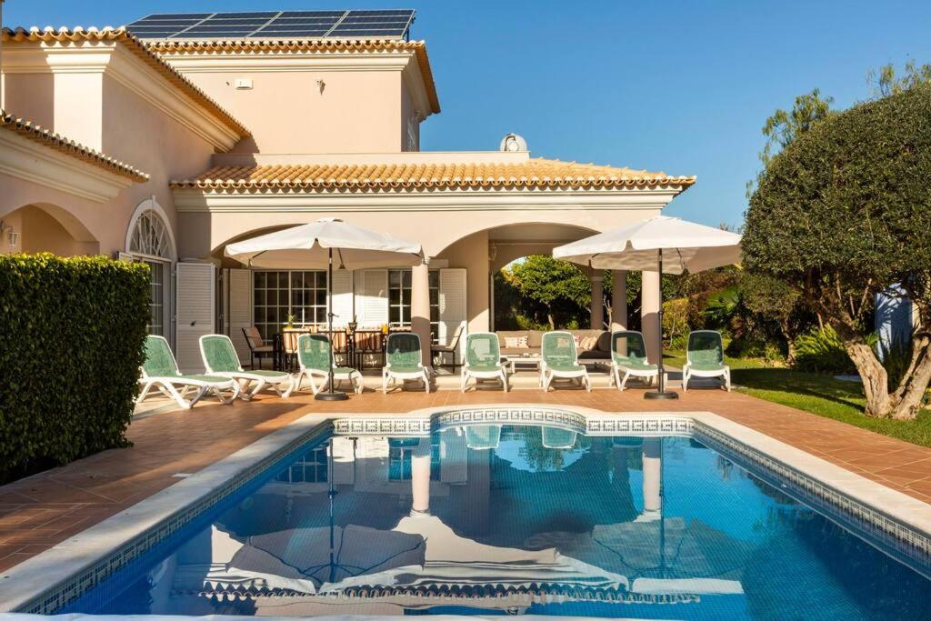 una casa con piscina con sedie e ombrelloni di Luxury Villa José with swimming pool a Quarteira