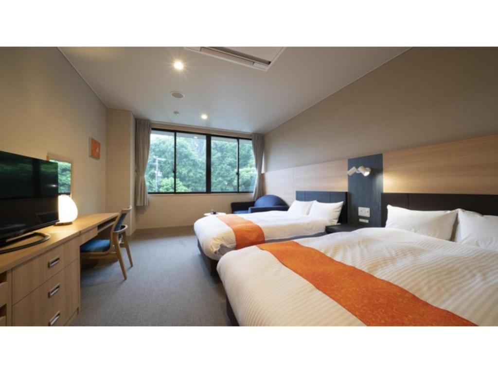 a hotel room with two beds and a flat screen tv at Hotel Sekisuien - Vacation STAY 44651v in Gujo