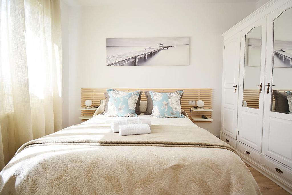 a white bedroom with a large bed with blue pillows at GALIHOST - A Casa do Olivo in Meis