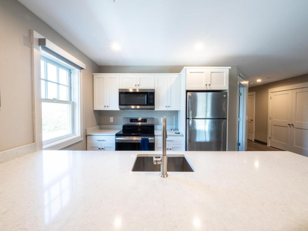 uma cozinha com armários brancos e electrodomésticos de aço inoxidável em Long Beach Suites em Gloucester