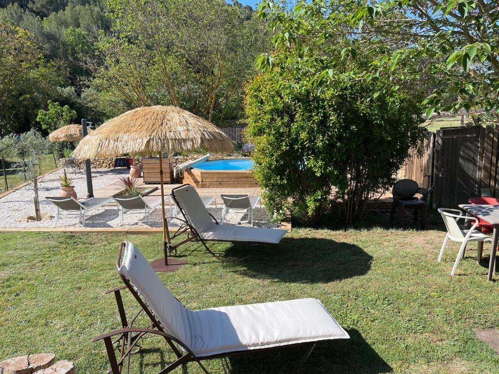 um grupo de cadeiras, um guarda-sol e uma piscina em L Atelier gîte 3 étoiles avec piscine Le Jas des Oliviers em Le Castellet