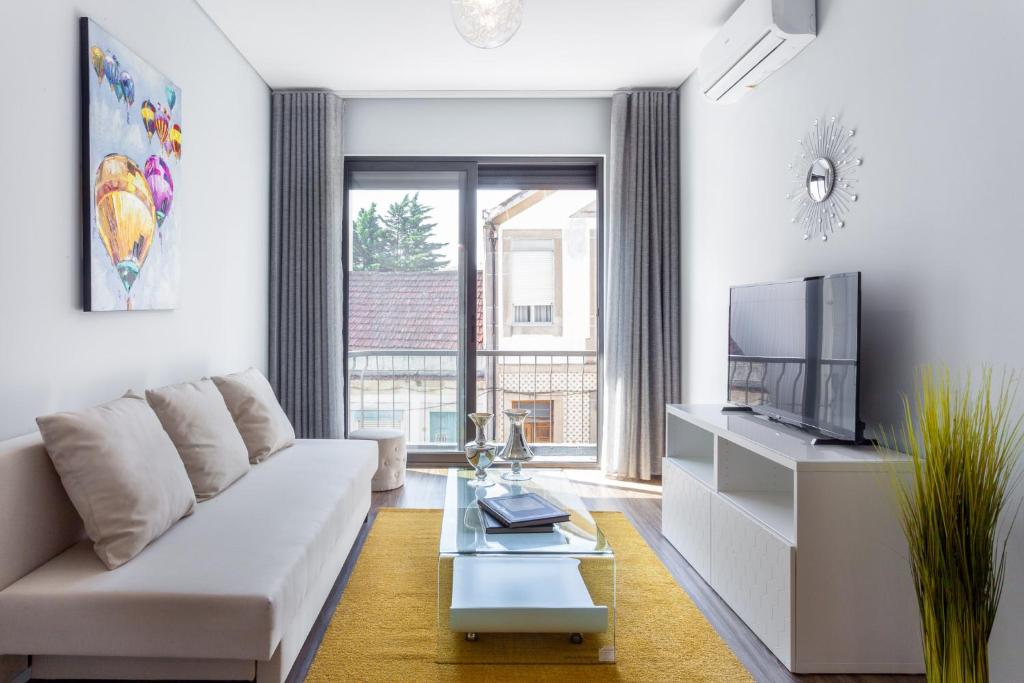 uma sala de estar com um sofá branco e uma televisão em Urban Views - ML Apart Inspired by Palácio de Cristal no Porto