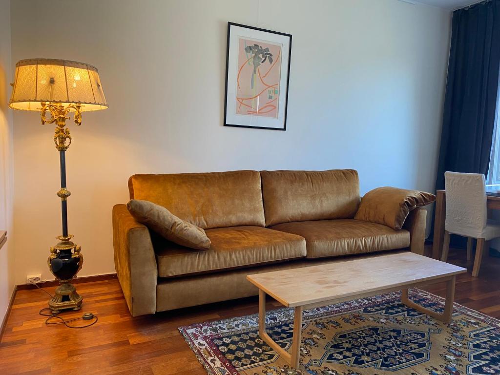 uma sala de estar com um sofá castanho e uma mesa em Parkview K10 em Helsinque