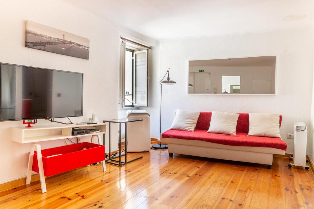 uma sala de estar com um sofá vermelho e uma televisão de ecrã plano em Studio in the heart of Alfama! Super Central! em Lisboa