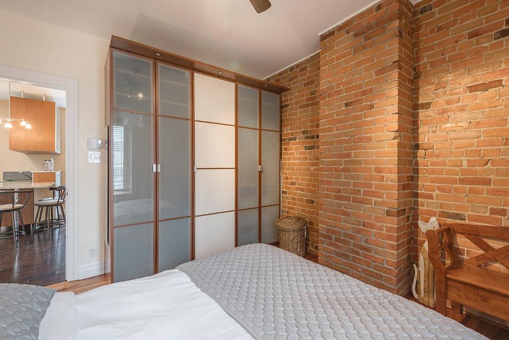 Un dormitorio con una pared de ladrillo y una cama en Apartment et Studio montreal, en Montreal