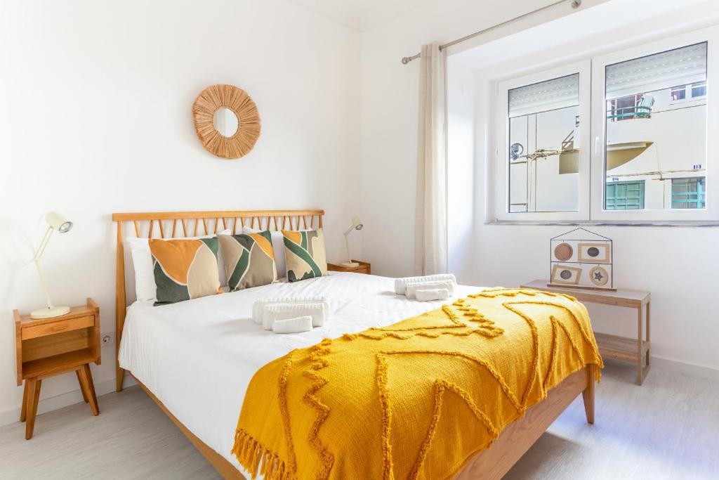 ein Schlafzimmer mit einem Bett mit einer gelben Decke darauf in der Unterkunft Wonderful Brand New Apartment Belém - A few steps away from the River! in Lissabon