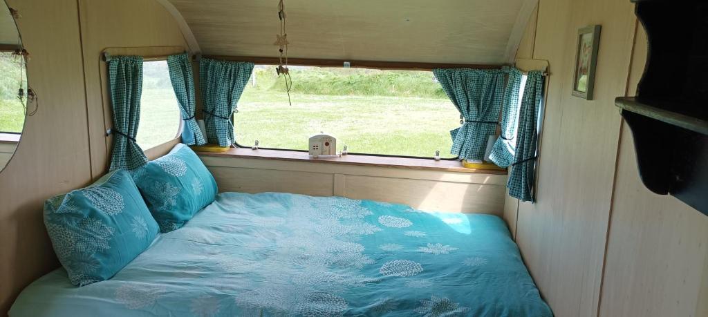 una cama en la parte trasera de una caravana con una ventana en Camping Les Ronds Duval face aux îles anglo-normandes, en Les Moitiers-dʼAllonne