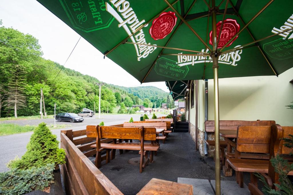 un restaurant avec des bancs en bois et un parasol vert dans l'établissement Penzion Hubert, à Mikulov v Krušných Horách