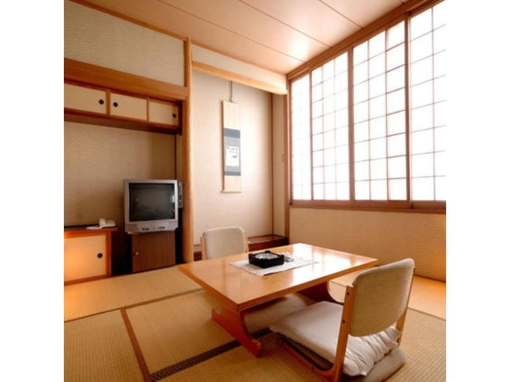 Pokój ze stołem, krzesłami i telewizorem w obiekcie Tennen Onsen Kakenagashi no Yado Hotel Pony Onsen - Vacation STAY 50911v w mieście Towada